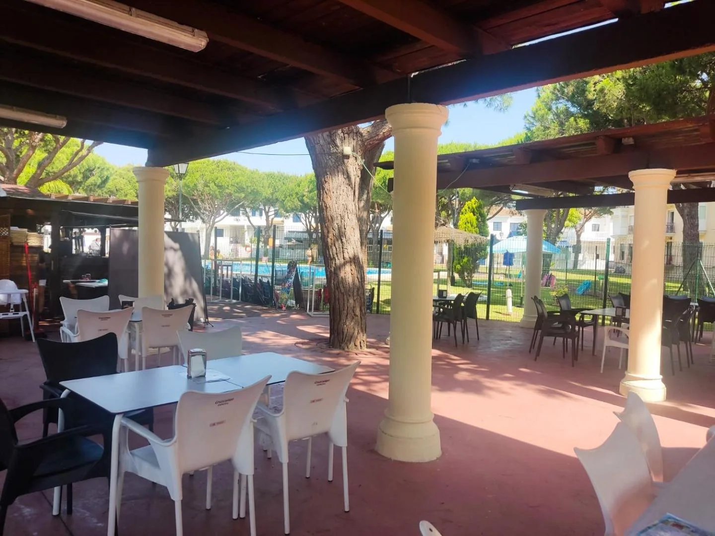 Terraza cubierta con mesas junto a la piscina
