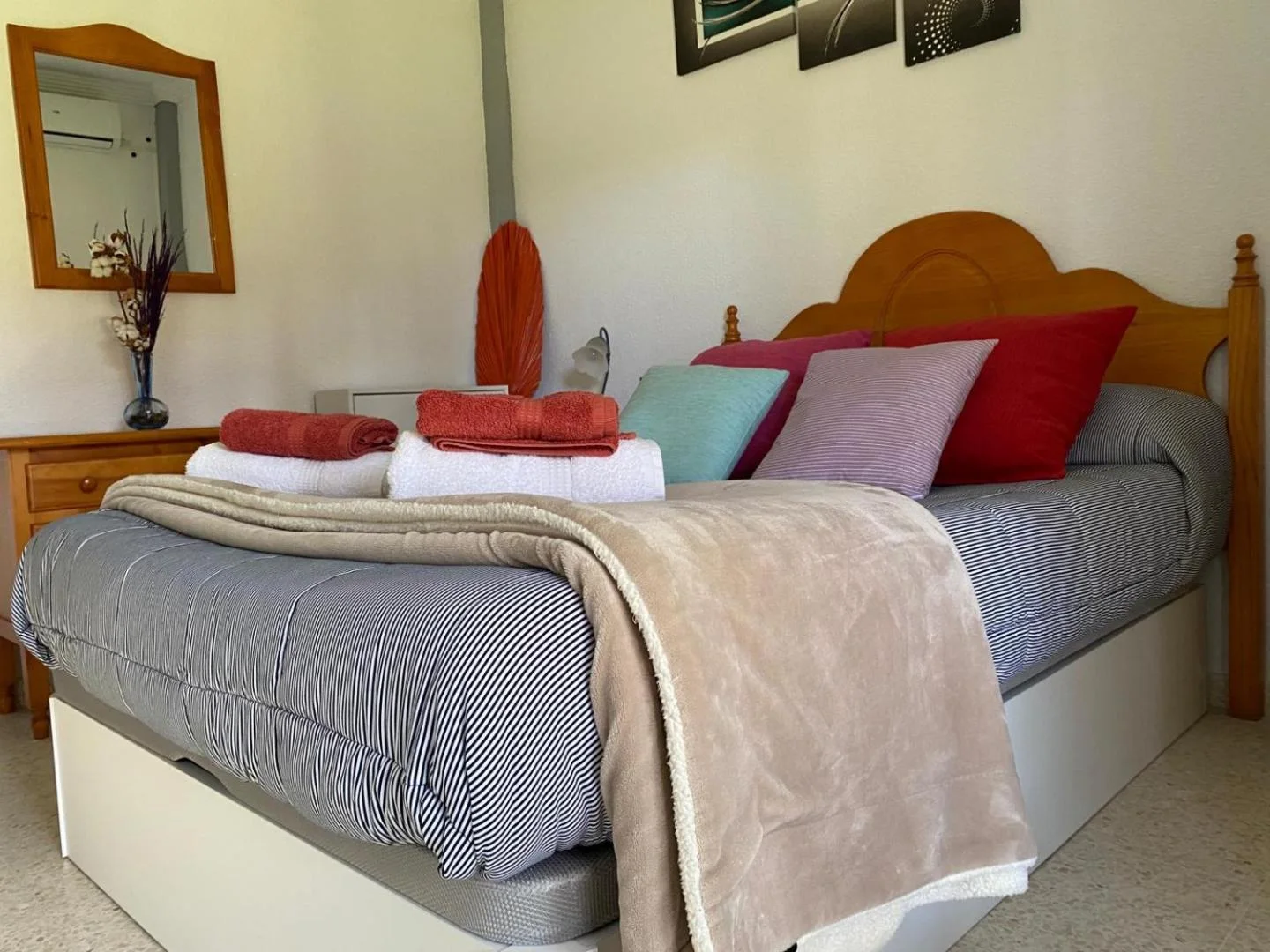 Dormitorio con cama doble, cabecero de madera y cojines de colores