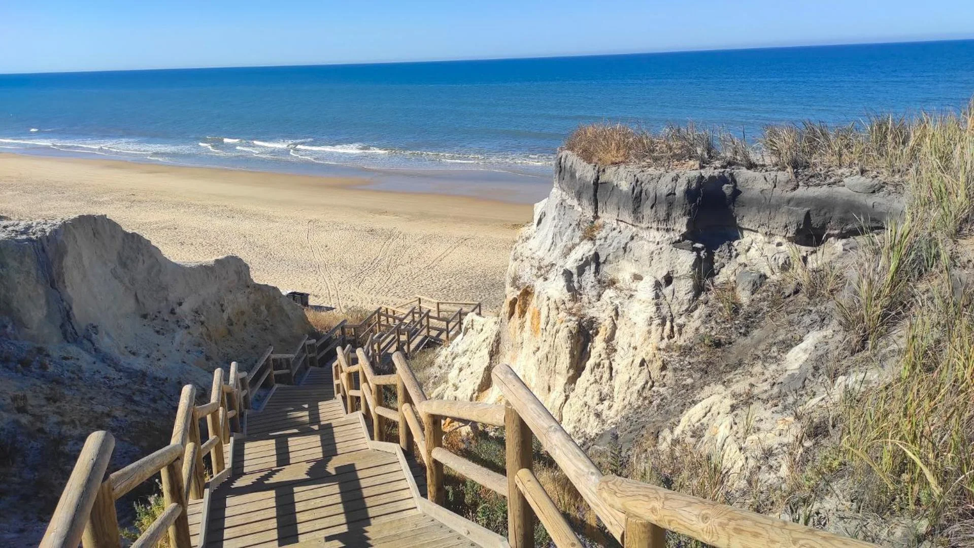 Pasarela de madera que baja entre acantilados a la playa de Mazagón